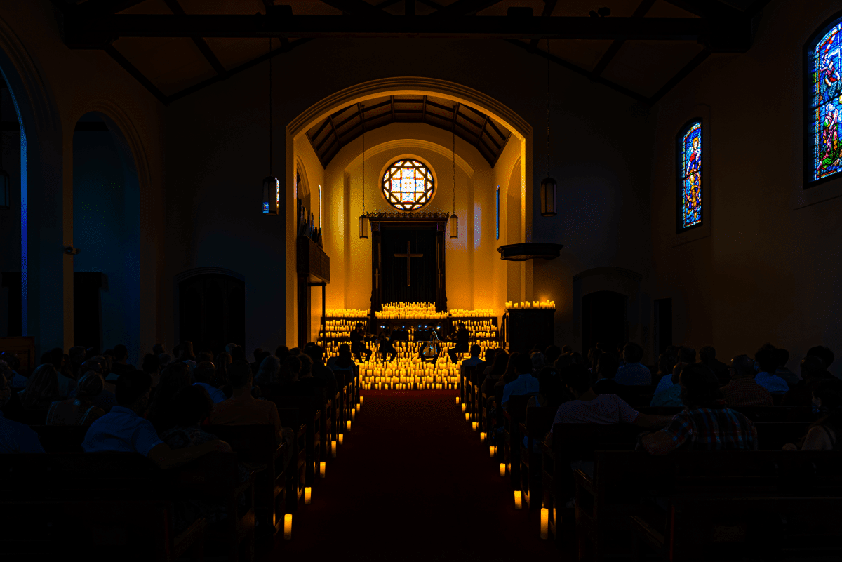 A dark shot revealing only the altar at the end of the aisle at Chapel in San Diego lit up by the glow of candlelight.
