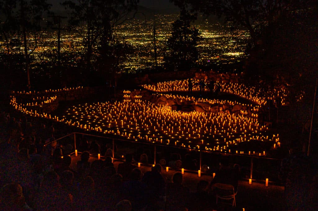 A birds eye view of Mt.Helix Park capturing a Candlelight concert taking place with candles everywhere and lights from the city visible in the background.