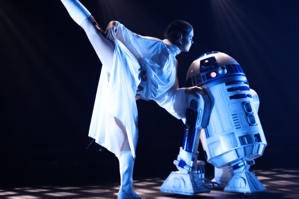 A dancer dressed as Princess Leia from Star Wars dances with a robot on a stage