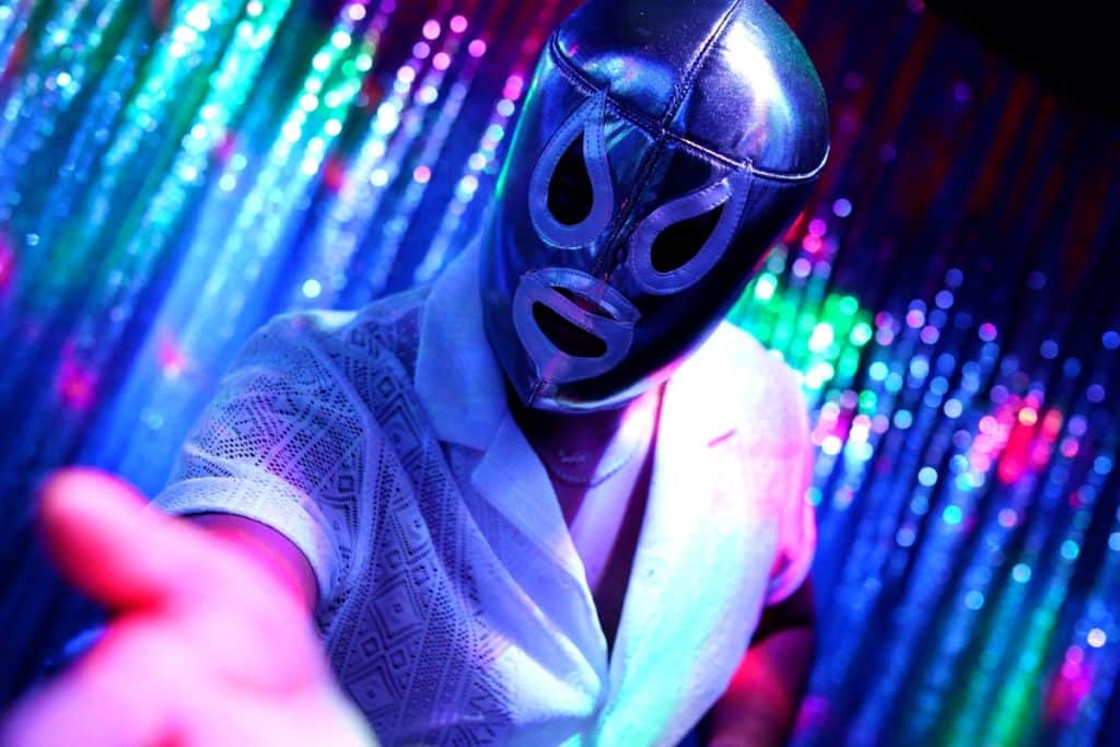A masked wrestler reaches towards the camera