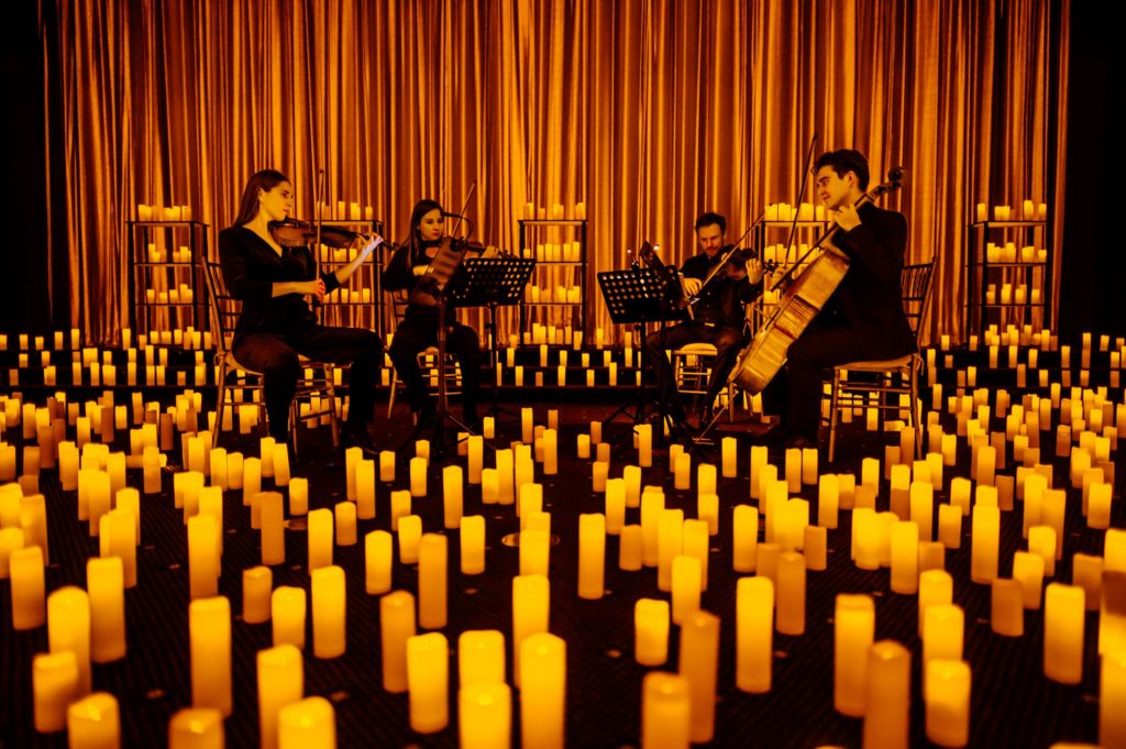 A string quartet performing a Candlelight concert surrounded by candles.