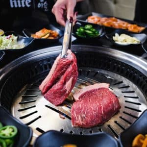 Customer grilling their own meats at Gen Korean BBQ House in San Diego