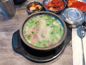 Korean noodle soup dish with sides from Woomiok in San Diego