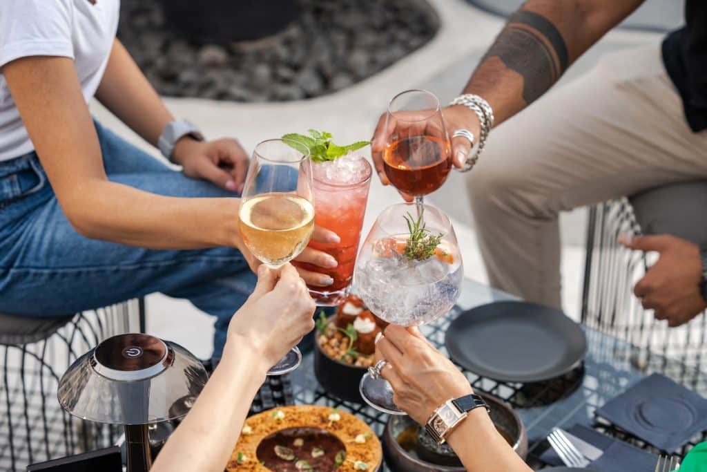 A group of friends toasting with a bunch of colorful cocktails