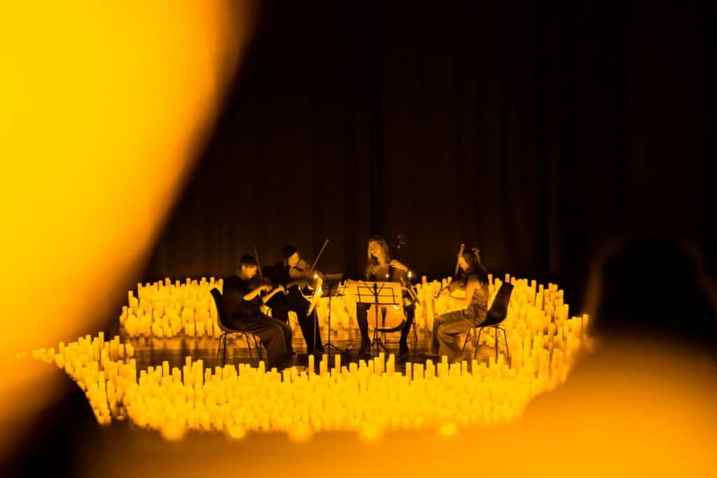 A string quartet performing a Candlelight concert surrounded by flickering candles.